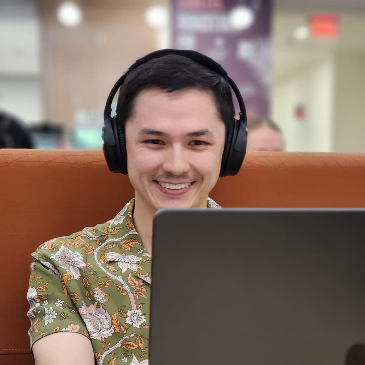 Hugh Berryman working on a laptop while wearing headphones.